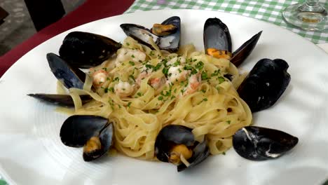 Tradicional-mediterránea-pasta-con-mejillones-y-mariscos-en-un-tradicional-plato-Mediterráneo-acompañado-con-frutas---Grecia,-Croacia,-Italia,-montenegro,-calamar-y-verduras-de-verano.