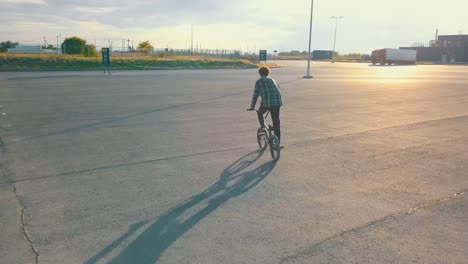 fliegende-Kamera-Junge-männliche-Jugendliche-Reiter-auf-dem-bmx-Rad-auf-der-leeren-städtischen-Stelle,-die-keine-Menschen-asphalt