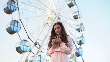The-girl-is-using-a-smartphone-standing-near-the-Ferris-wheel-.4K