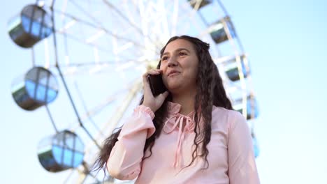 The-girl-is-talking-on-the-phone-standing-near-the-Ferris-wheel-.4K