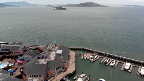 Disparo-aéreo-volando-hacia-atrás-sobre-Pier-39-y-los-barcos-circundantes-en-San-Francisco,-California