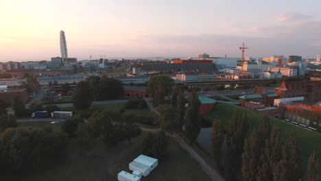 Toma-aéreo-sobrevolando-abajo-ciudad-de-Malmo-en-puesta-del-sol.-El-Turning-Torso-en-el-fondo