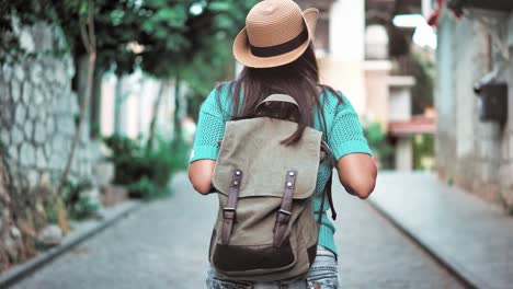 Mujer-de-mochila-de-excursionista-activo-posterior-vista-en-sombrero-caminando-por-la-calle-estrecha-de-la-acogedora-ciudad-europea