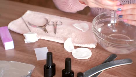 Woman-cuts-cuticle-with-nipper.-Makes-manicure-herself.-Close-up-hands.-Manicure-tools-on-the-table.