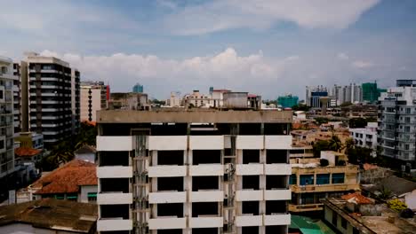 Drone-rising-over-sunny-city-of-Colombo,-Sri-Lanka.-Beautiful-aerial-shot-of-modern-coastline-buildings-and-cloudy-sky