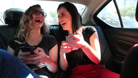 Candid-real-laugh-of-friends-holding-their-cellphone-in-the-back-seat-of-a-car