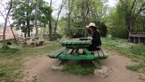 junge-und-schöne-Frau-spielen-Synthesizer-auf-dem-Tisch-eines-Parks,-Frankreich