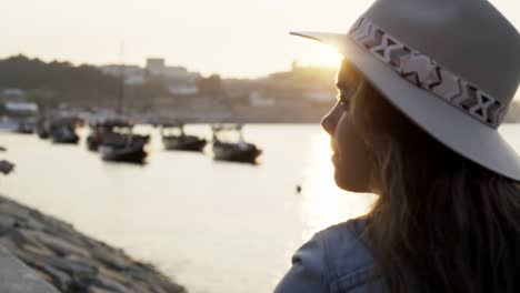 Young-lady-relaxing-on-embankment-at-sunset