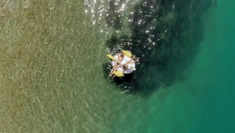 Luftaufnahme-von-zwei-Frauen,-die-in-Panagopoula,-Griechenland,-auf-aufblasbare-Weise-schwimmen.