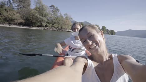 Young-couple-on-Summer-vacation-enjoying-canoe-on-the-lake-in-the-mountains.-People-travel-fun-holidays-concept.-Technology-and-youth-culture-taking-selfie---4K