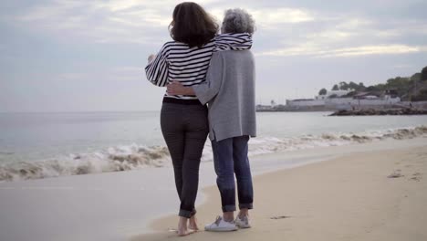 Two-smiling-women-hugging-on-seacoast.