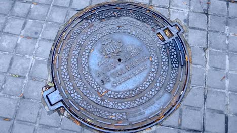 Metal-sewer-manhole-on-the-street-of-Valencia,-Spain-with-national-pattern