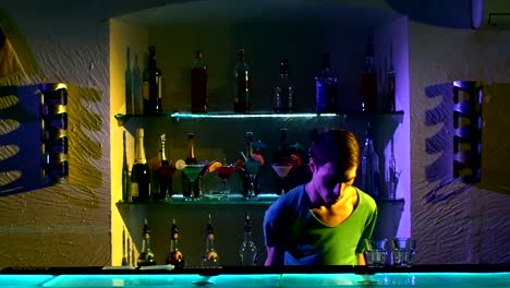 Barman-joven-haciendo-trucos-con-dos-copas-y-una-botella-standing-behind-the-bar,-cámara-lenta