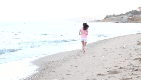 muchacha-en-la-mañana-corre-a-lo-largo-de-la-playa-cerca-del-mar