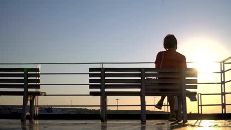 Silhouette-of-a-senior-woman-sitting-on-a-cruise-ship-yacht-deck-at-sunset