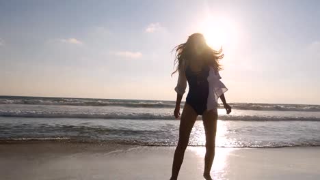 Happy-woman-running-and-spinning-on-the-beach-near-the-ocean.-Young-beautiful-girl-enjoying-life-and-having-fun-at-sea-shore.-Summer-vacation-or-holiday.-Nature-landscape-at-background