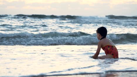 Niña-jugando-en-la-playa-en-el-agua-durante-la-hora-del-atardecer