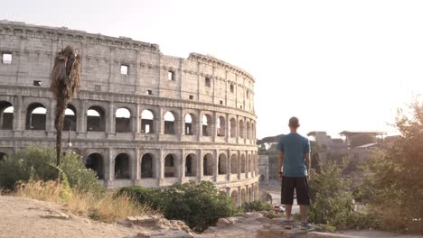 Man-in-sportswear-standing-on-a-hill-in-front-of-the-Colosseum-in-Rome-after-running-at-sunset-and-checking-time-on-his-watch
