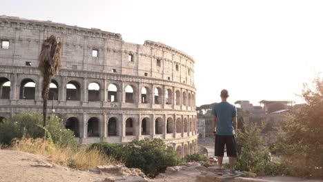 Hombre-en-situación-deportiva-en-una-colina-frente-al-Coliseo-de-Roma-después-de-correr-al-atardecer-y-comprobar-la-hora-en-su-reloj