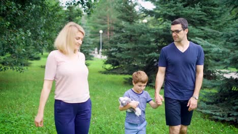 Adult-parents-and-little-boy-walking-together-in-green-park