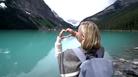 Mujer-joven-haciendo-forma-marco-de-corazón-en-Lake-Louise