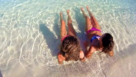 Smiling-little-girls-laying-in-water-on-the-beach