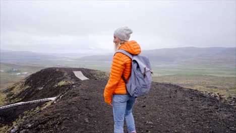 Slow-motion-Hiking-woman-gesturing-come-along-follow-me,-waving-and-hand-looking-at-camera,-Iceland