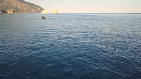 aerial-drone-flying-shot-of-cruise-touristic-catamaran-passing-by-the-sea-rocky-coast