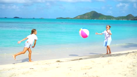 Kleinen-niedlichen-Mädchen-spielen-mit-Kugel-am-Strand