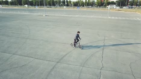 flying-view-of-young-rider-doing-tricks-on-bmx-bike-in-the-urban-street-on-asphalt-surface