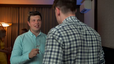 Two-smiling-guys-speaking-at-party