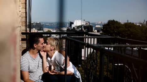 Feliz-pareja-romántica-multiétnico-relajado-sentadas-muy-juntas-en-un-balcón-de-hermosa-mañana-soleada-en-Nueva-York