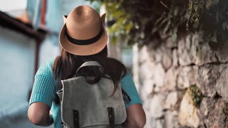 Steadicam-establish-shot-rear-view-backpacker-tourist-woman-enjoying-walking-narrow-street