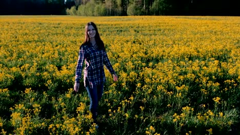 Brünette-Frau-dreht-sich-mitten-auf-einem-Feld-mit-gelben-Blüten.