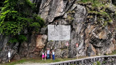 OROPA,-BIELLA,-ITALY---JULY-7,-2018:-aero-View-of-beautiful-large-inscription-on-rock-near-Shrine-of-Oropa,-sanctuary-located-in-mountains.-Tourists-walking-in-park-in-mountains