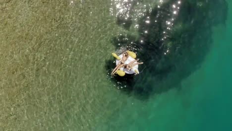 Vista-aérea-de-dos-mujeres-flotando-en-inflable-en-Panagopoula,-Grecia.