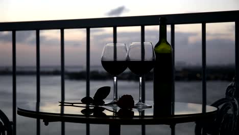 Noche-romántica-con-vino-tinto-en-el-balcón-al-atardecer