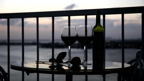 Romantic-evening-with-red-wine-on-balcony--at-sunset