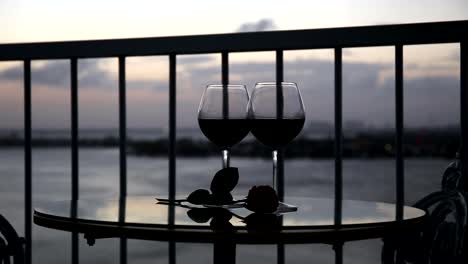 Noche-romántica-con-vino-tinto-en-el-balcón-al-atardecer