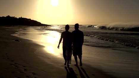 Couple-enjoying-romantic-walk-along-the-beach-in-silhouette,-Cape-Town,South-Africa