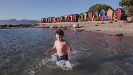 Junge-läuft-in-Richtung-Kamera-im-St-James-beach,-Kapstadt,-Südafrika