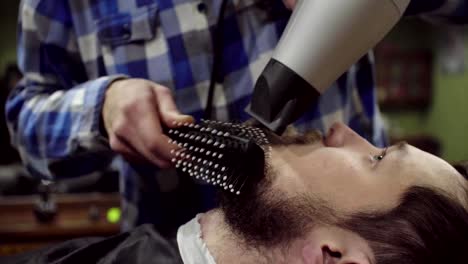 Barber-is-drying-beard-a-bearded-man-with-hairdryer-in-a-barber-shop