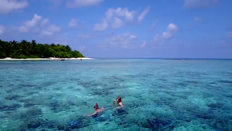 v04066-vista-aérea-de-drone-volando-de-Maldivas-playa-2-personas-pareja-joven-hombre-mujer-snorkel-natación-buceo-en-la-isla-de-paraíso-tropical-soleado-con-cielo-azul-aqua-agua-mar-4k