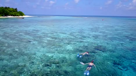 v04059-fliegenden-Drohne-Luftaufnahme-der-Malediven-weißen-Sandstrand-2-Personen-junges-Paar-Mann-Frau-Schnorcheln-Schwimmen-Tauchen-auf-sonnigen-tropischen-Inselparadies-mit-Aqua-blau-Himmel-Meer-Wasser-Ozean-4k