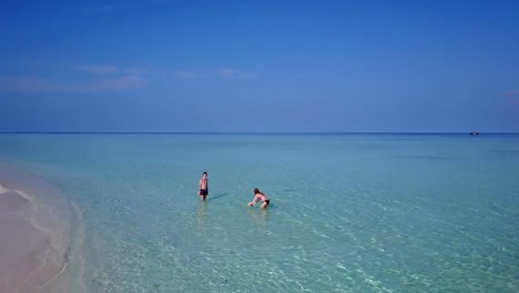 v04196-fliegenden-Drohne-Luftaufnahme-der-Malediven-weißen-Sandstrand-2-Personen-junges-Paar-Mann-Frau-Schwimmen-unter-Wasser-plantschen,-auf-sonnigen-tropischen-Inselparadies-mit-Aqua-blau-Himmel-Meer-Wasser-Ozean-4k