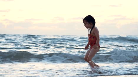 Kleine-Mädchen-spielen-am-Strand-im-Wasser-während-Sonnenuntergang-Stunde