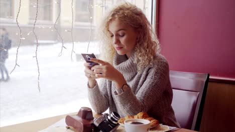 Young-curly-woman-sitting--in-cafe-with-phone