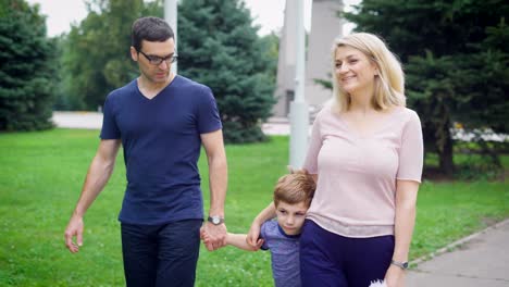 Fröhliche-Mutter-und-Vater-mit-kleinen-Sohn-zu-Fuß-auf-Park-im-Sommer