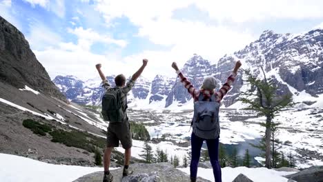Happy-couple-arms-raised-foe-achievement-and-success-at-mountain-top