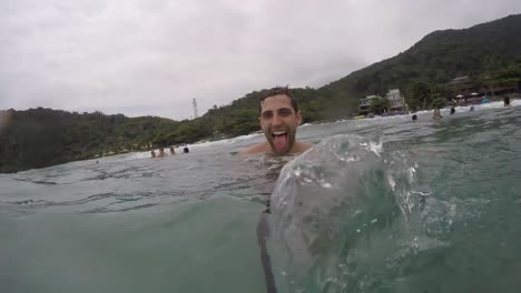 Chico-brasileño-joven-divirtiéndose-y-teniendo-un-selfie-en-la-playa